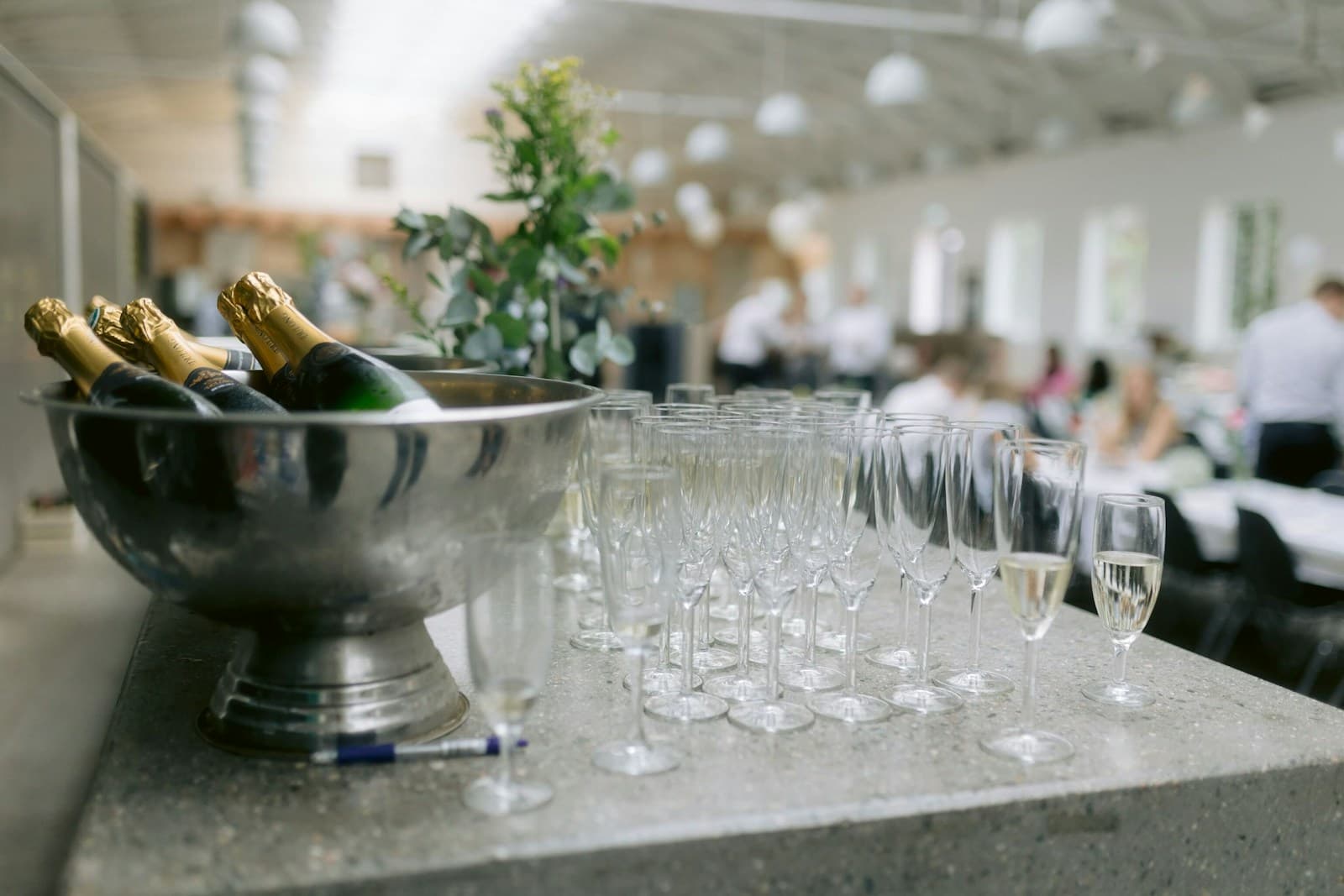 Chilled sparkling-wine bottles beside rows of clean glasses in a naturally lit hospitality room