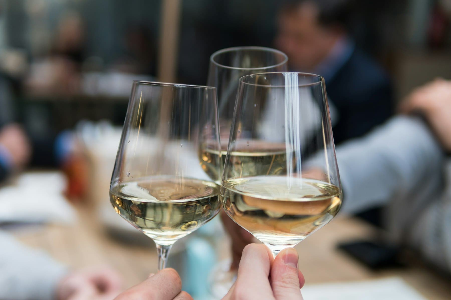 White wine glasses are raised during a professional tasting.