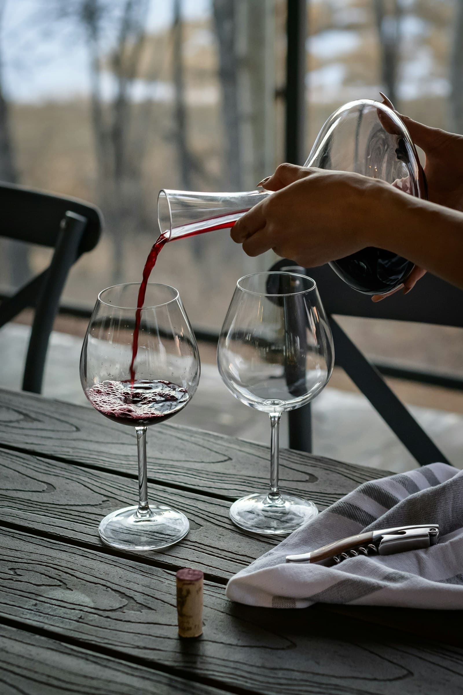 Red wine poured from a glass decanter at a dining table