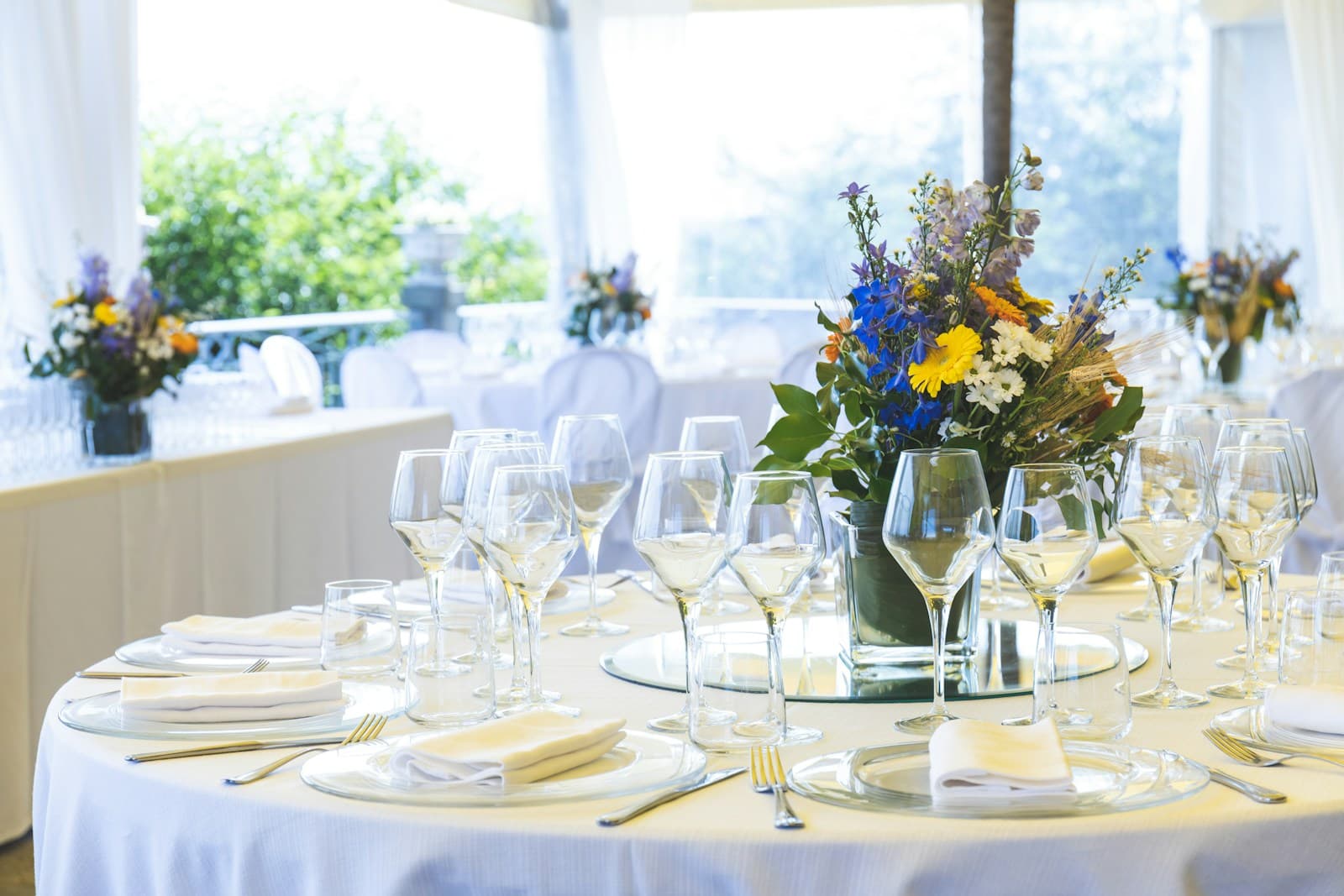 Wine glasses and flowers arranged on a bright formal dining table