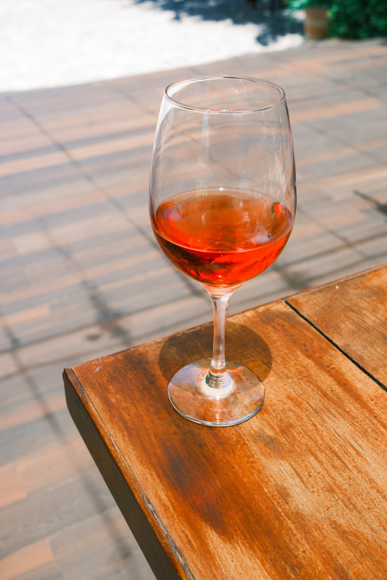 A glass of rosé catching the light on a wooden table