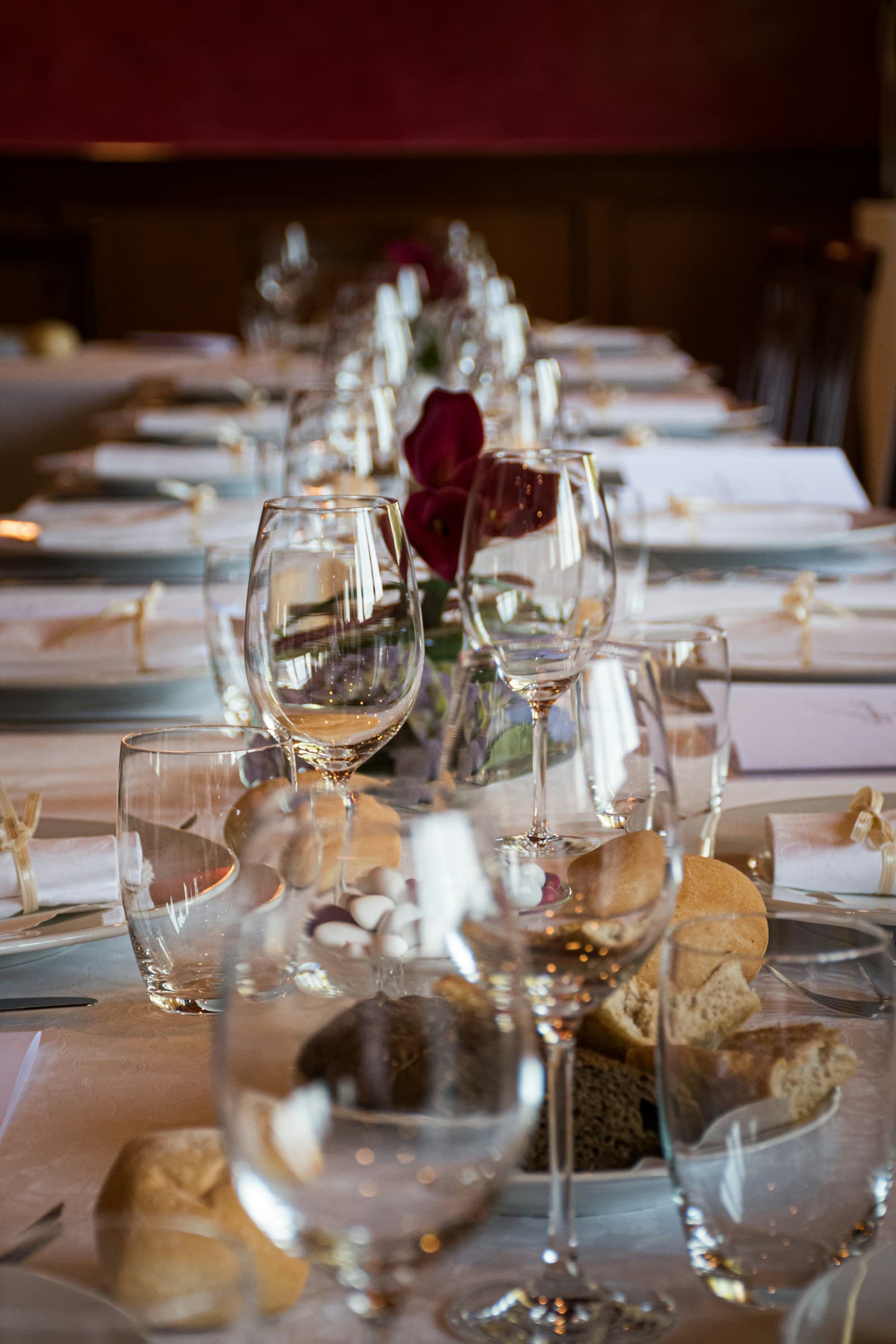 Wine glasses and burgundy floral accents on a celebration table